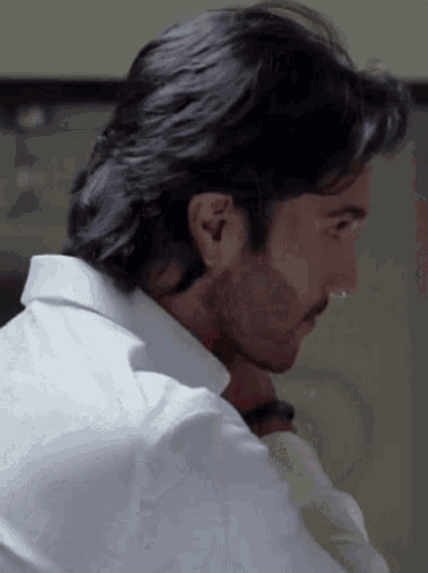 a man with long hair and a beard wearing a white shirt and tie
