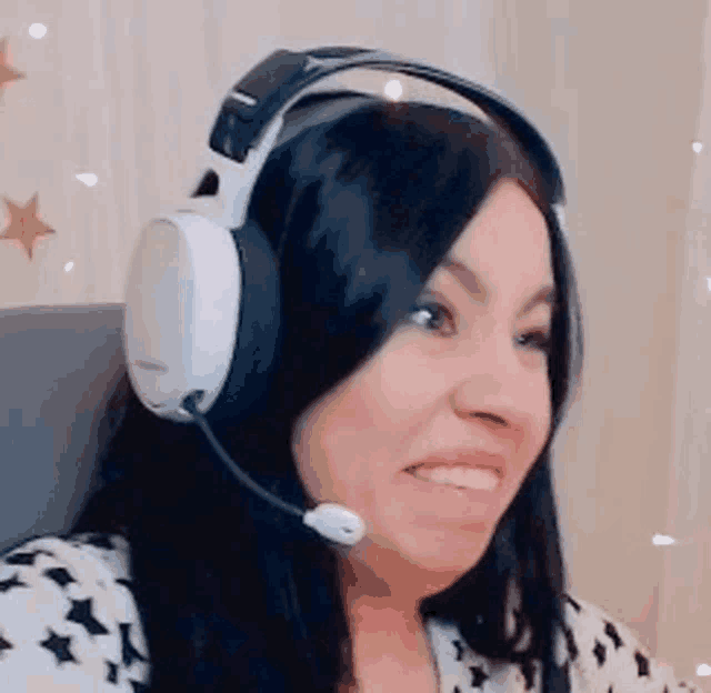 a woman wearing headphones and a microphone is smiling and making a funny face .