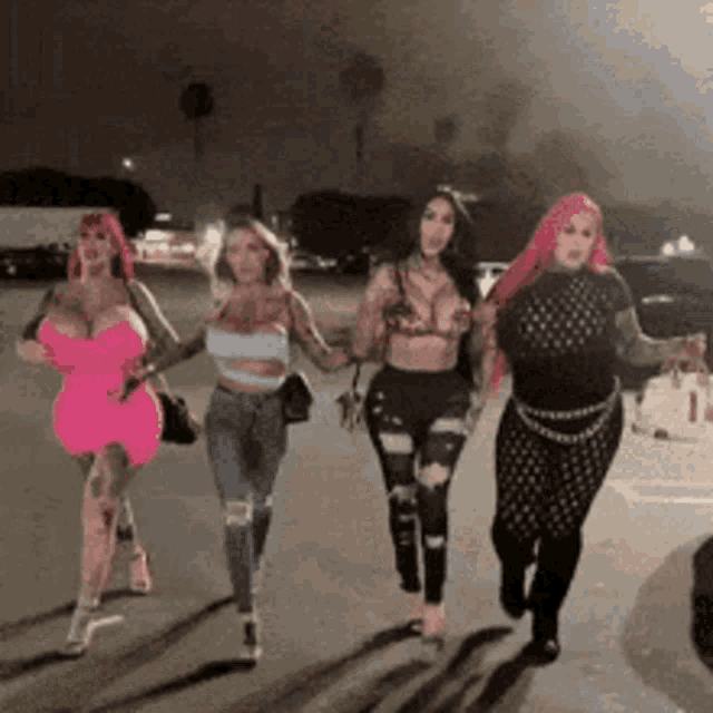 a group of women are walking down a street at night .