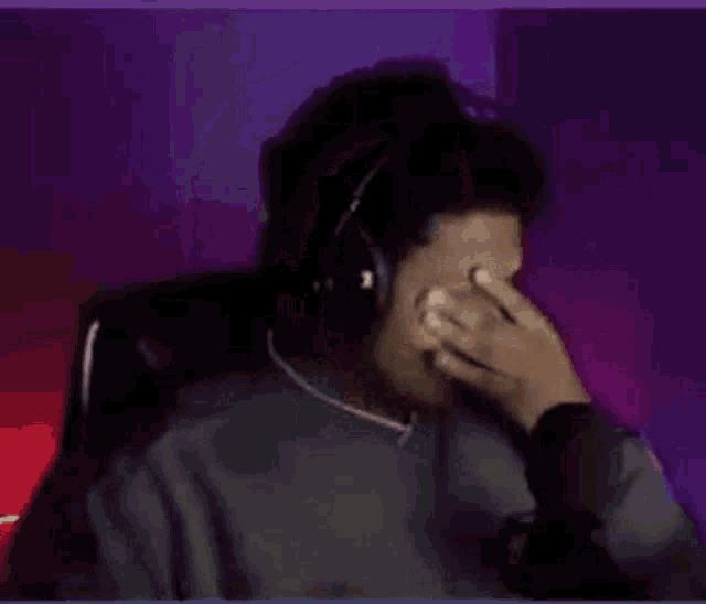 a person wearing headphones is drinking through a straw while sitting at a table .