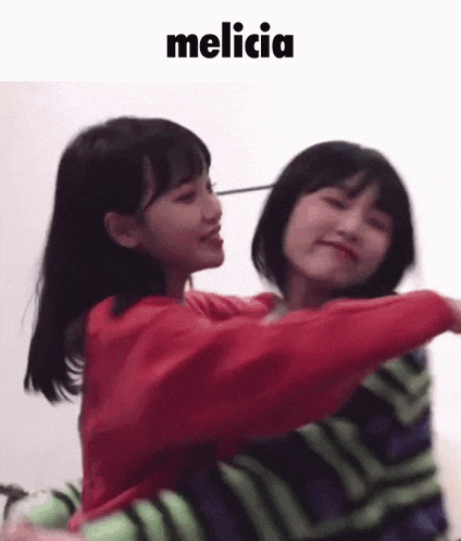 a couple of girls are hugging each other and one of them is wearing a green striped shirt .