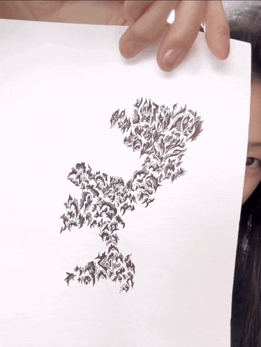 a woman is holding a piece of paper with a drawing of a tree on it