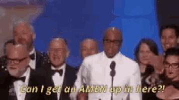 a group of men in tuxedos are standing in front of a microphone and talking .