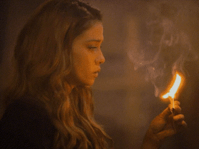 a woman is lighting a match in her hand