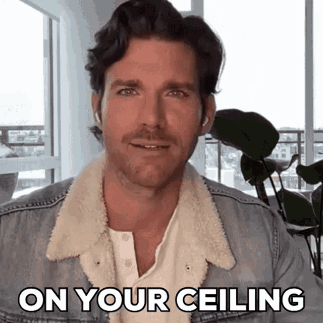 a man is wearing a denim jacket and says on your ceiling .