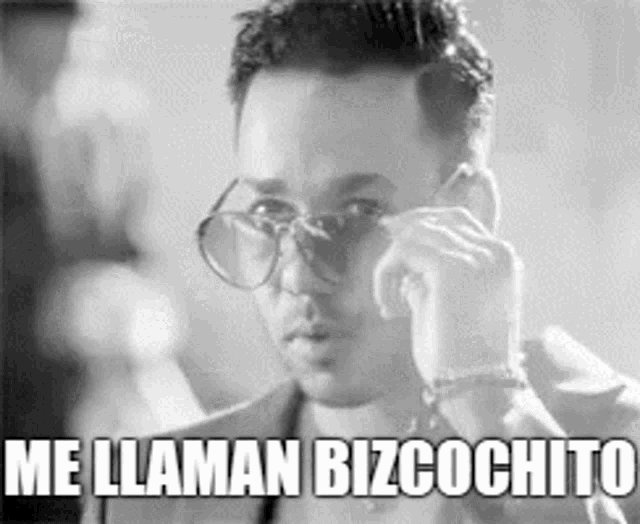 a black and white photo of a man wearing glasses and a suit talking on a cell phone .