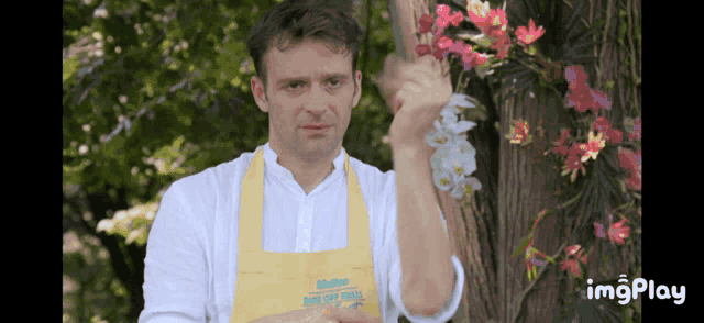 a man wearing a yellow apron that says bake off finale