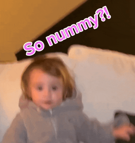 a little girl is laying on a bed with the words so nummy written above her head