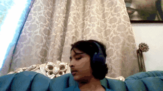 a young girl wearing headphones is sitting on a blue couch