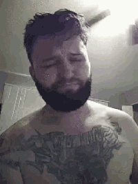 a shirtless man with a beard and tattoos on his chest