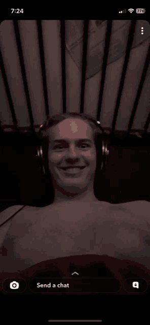 a man without a shirt is wearing headphones and smiling on a phone screen that says " send a chat "