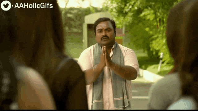 a man with his hands folded in front of a group of people with aaholicgifs written on the bottom of the screen