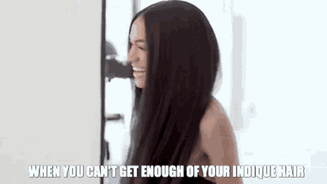 a woman with long black hair is looking at herself in the mirror .