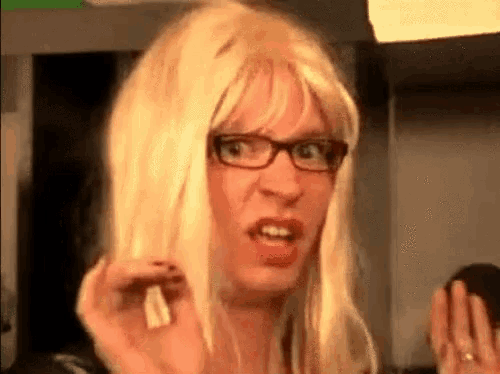 a man wearing a blonde wig and glasses is making a funny face .