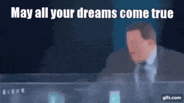 a man in a suit and tie is sitting in front of a computer screen with the words may all your dreams come true above him