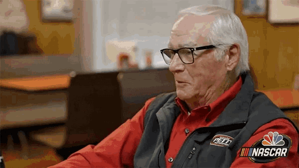 an older man wearing glasses and a vest that says nascar