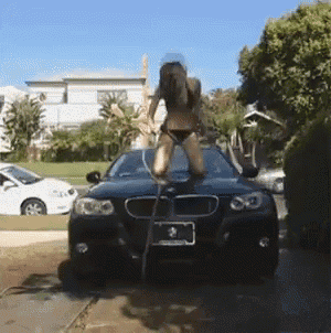 a woman in a bikini is standing on the hood of a bmw