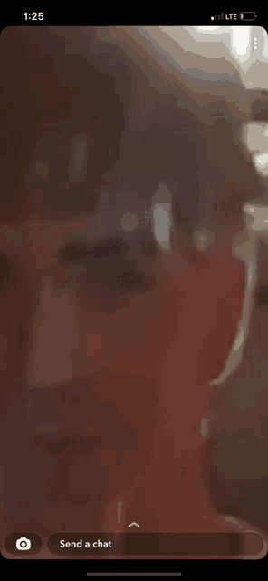 a phone screen shows a man 's face and says " send a chat "