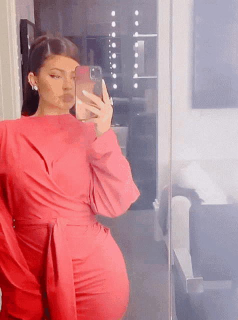 a woman in a red dress is taking a selfie in a mirror