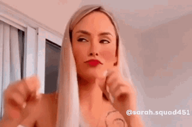 a woman with blonde hair is making a funny face with her hands