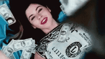 a woman is laying in a pile of money with a 1 dollar bill laying on her chest