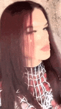 a woman with long red hair is wearing a spiderman costume and looking at the camera .