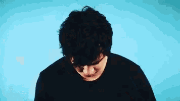 a man with curly hair is looking down with his eyes closed .