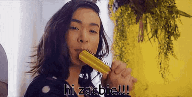 a woman is brushing her hair and says hi zachie