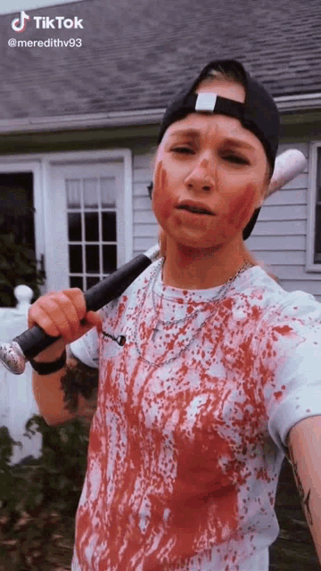 a woman with blood on her face is holding a bat