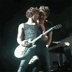 two men are playing guitars on a stage and one is wearing a shirt that says ' you '