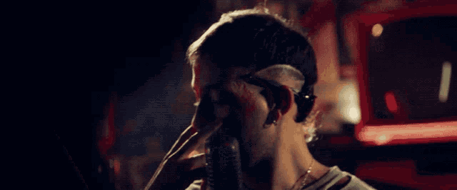 a man with blood on his face is singing into a microphone in a dark room