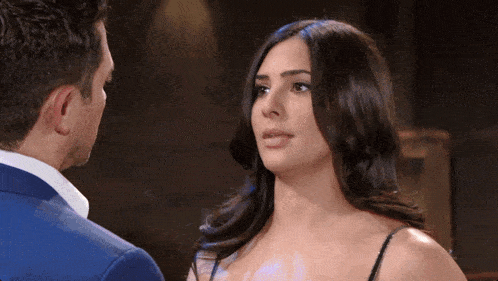 a man in a suit and a woman in a black dress are looking at each other