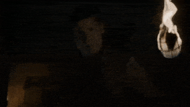 a person is holding a torch with flames coming out of it in the dark .