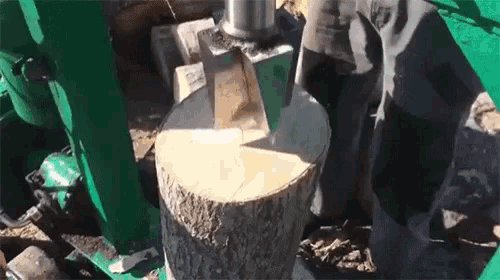a person is using a machine to chop a log .