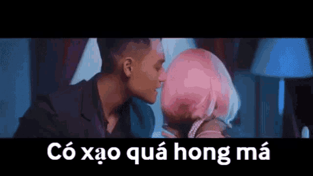 a man is kissing a woman with pink hair in a room .