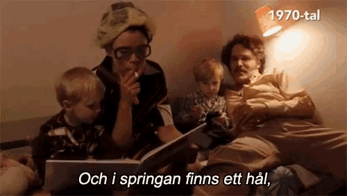 a woman is smoking a cigarette while reading a book to two children and the words och i springan finns ett hal are visible