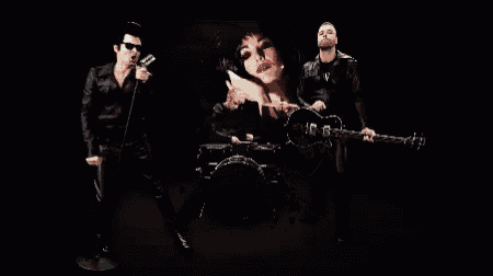 a man wearing sunglasses and a leather jacket is blowing a kiss into a microphone in the dark .