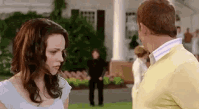 a man and a woman are looking at each other in front of a house .