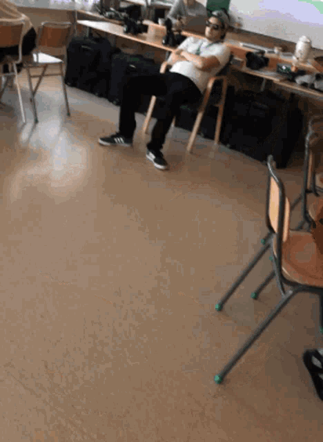 a man sits in a chair with his arms crossed in a classroom