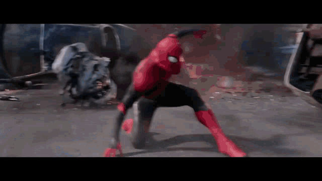 a man in a spiderman costume is kneeling down in front of a motorcycle .