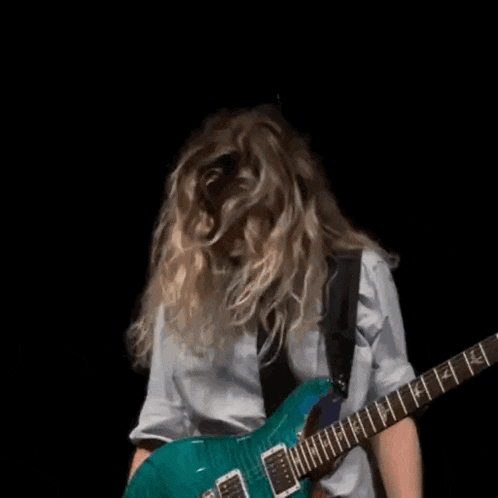 a woman in a white shirt and tie is holding a blue guitar .