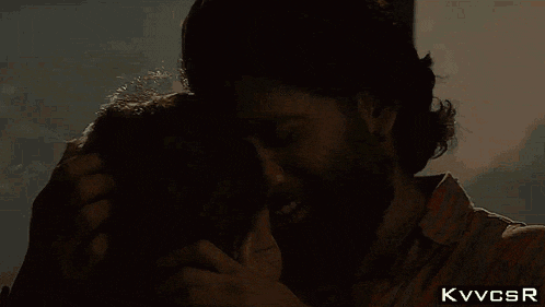 a man with a beard is hugging a woman with the letters kvvcsr above them