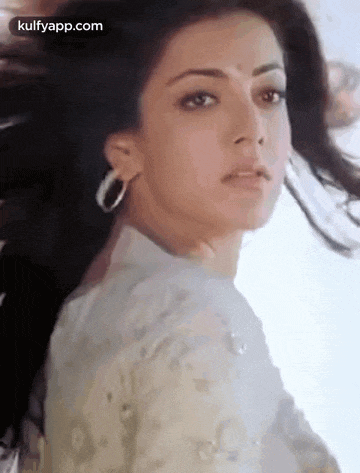 a close up of a woman 's face with her hair blowing in the wind and looking at the camera .