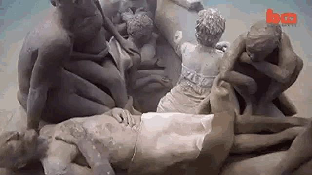 a group of clay statues are laying on top of each other on a beach .