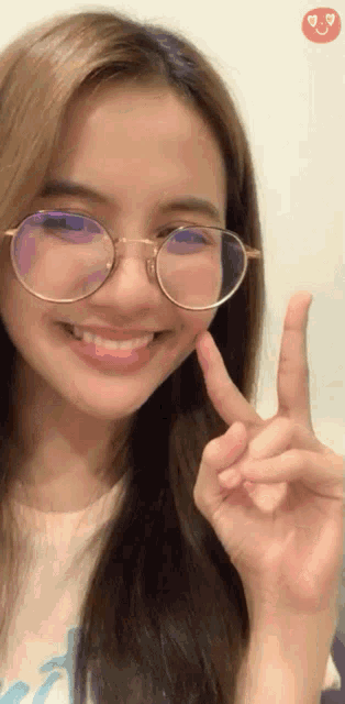 a woman wearing glasses giving a peace sign