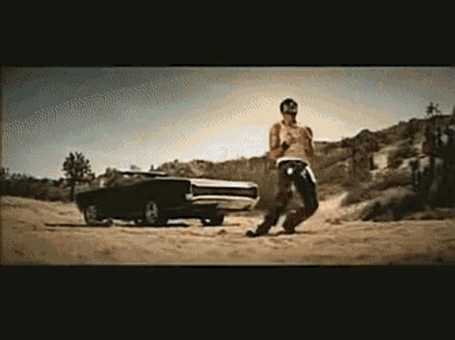 a man is standing next to a car in a desert
