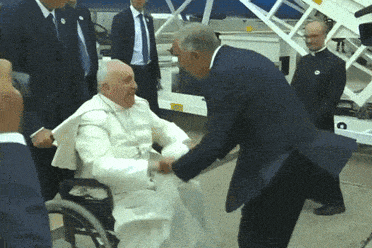 a man in a suit shakes hands with a man in a white robe