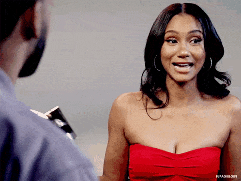 a woman in a red strapless dress is smiling at a man in a blue shirt