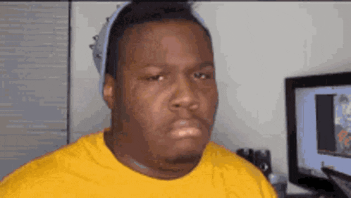a man wearing a yellow t-shirt and a hat is making a funny face .
