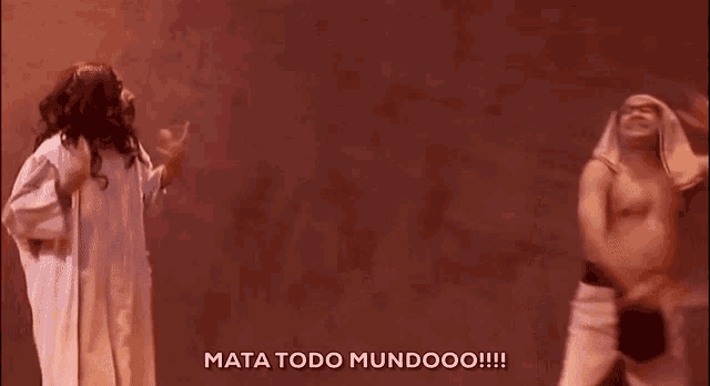 two men are dancing in front of a wall with mata todo mundoo written on the bottom right